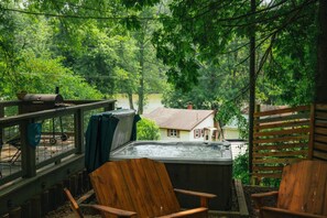 A hot tub on a wooden deck with a view of a house and trees.