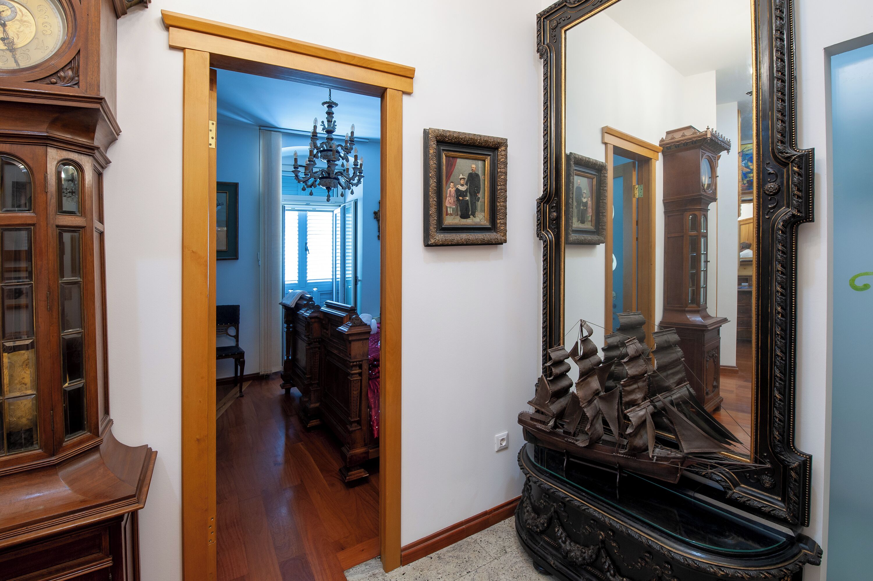 Un pasillo con muebles de madera, un espejo grande y una lámpara de araña.