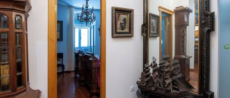 Un pasillo con muebles de madera, un espejo grande y una lámpara de araña.