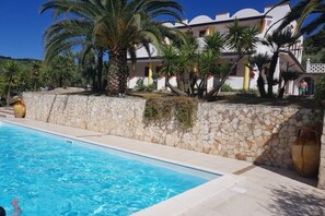 Una piscina con muro de piedra y palmeras.
