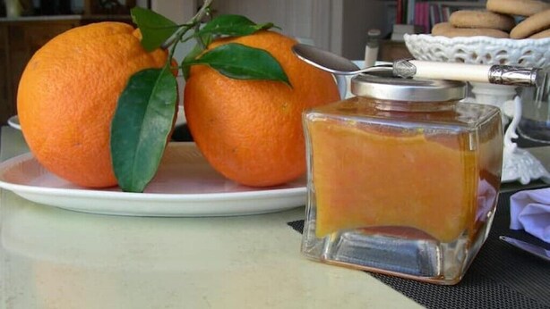 Deux oranges sur une assiette, à côté d’une bouteille en verre munie d’un bouchon en métal.