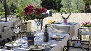 Een terras met tafels gedekt voor een maaltijd, omgeven door groen en planten.