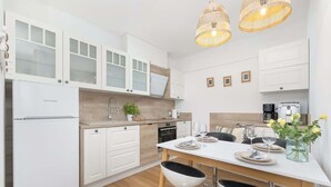 Una cocina moderna con armarios blancos, una mesa de comedor con sillas y una cafetera.