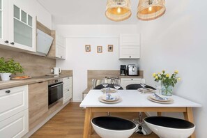 Une cuisine moderne avec des meubles blancs, une table à manger pour deux personnes et une machine à café.