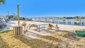 Un espace aménagé au bord de la plage, avec des tables de pique-nique, un barbecue et un bateau.