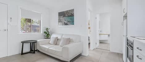 Un intérieur moderne et épuré, avec un canapé, une petite table et un coin cuisine.