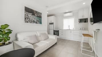 A modern living room with a white sofa, a coffee table, and a potted plant.