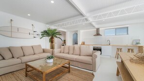 A modern living space with a sofa, coffee table, and a kitchen area with a dining table. - Recently refurbished, our airy and inviting self-contained lower duplex comfortably accommodates up (Crescent Head)