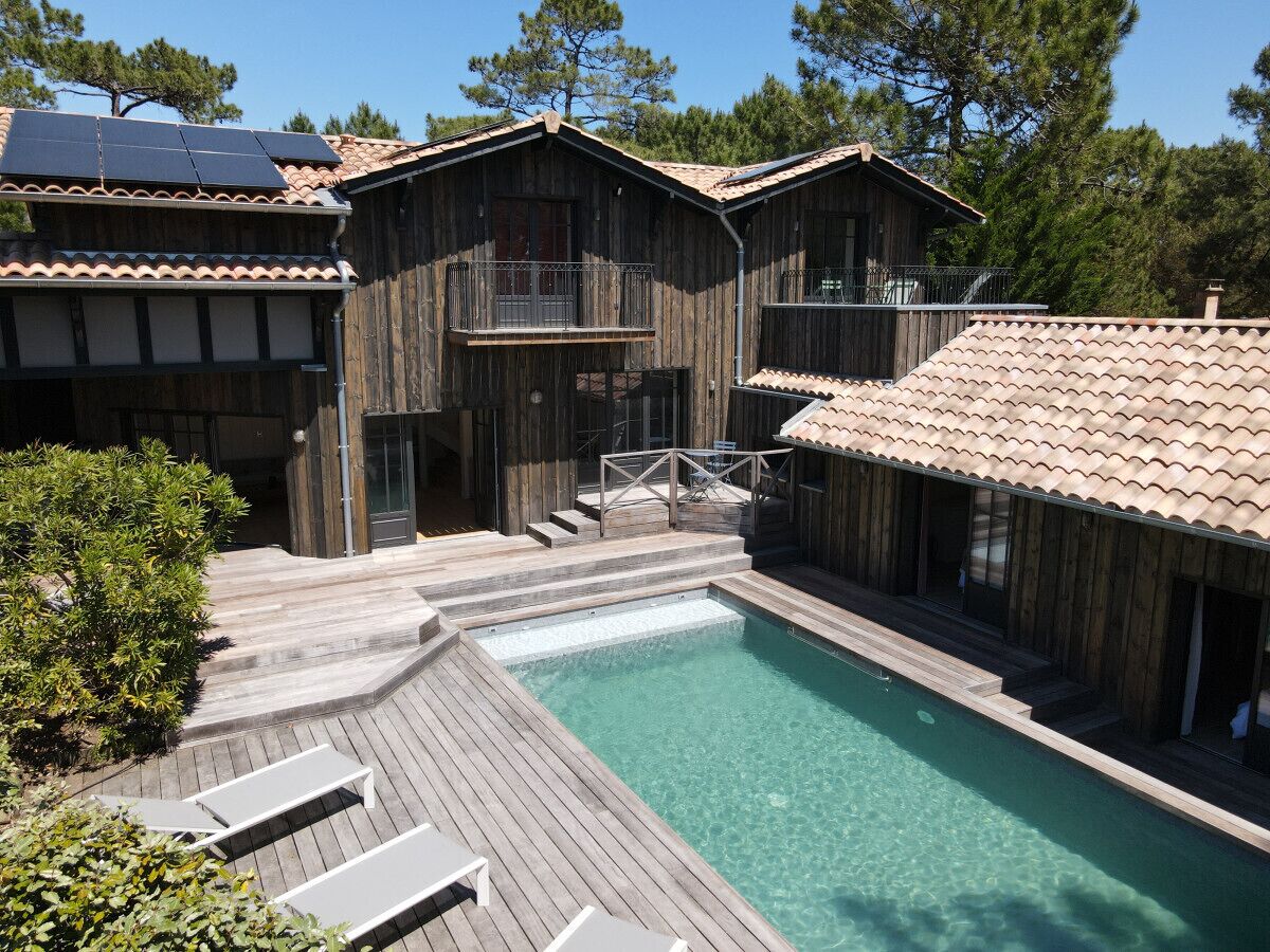 A wooden cabin with a swimming pool, wooden deck, and a balcony.