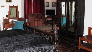 Una habitación con una cama, un armario de madera, un televisor y un sofá.
