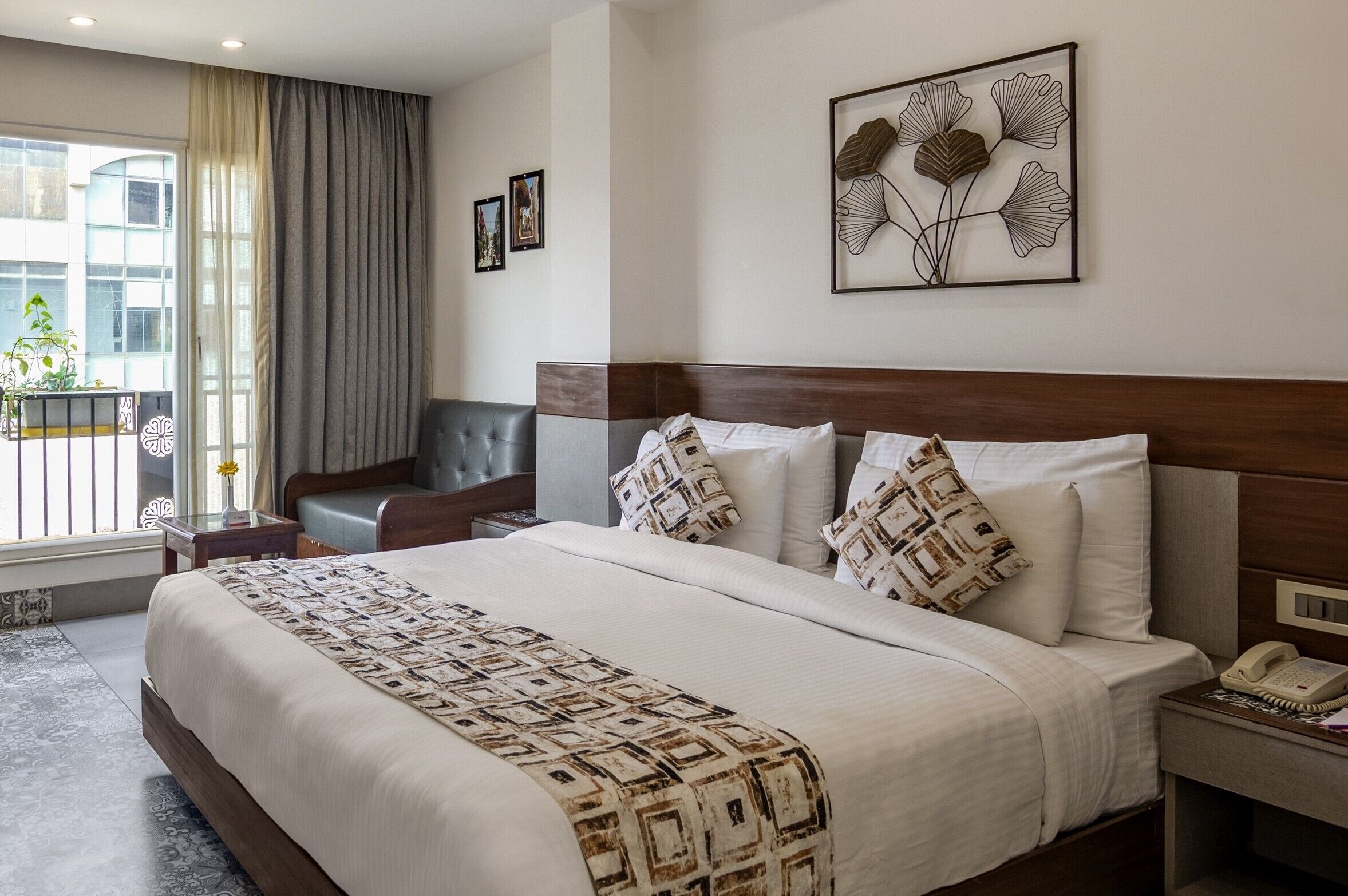 A hotel room with a large bed, a wooden headboard, a bedside telephone, and a window with curtains.