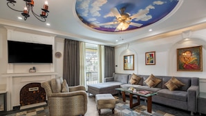 A living room with a fireplace, a sofa set, a television, and a ceiling fan. - Sterling Marbella Dehradun (Dehradun)