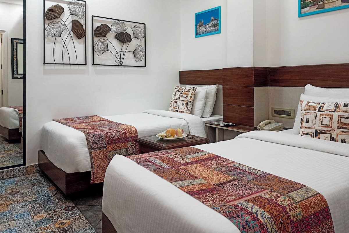 Habitación de hotel con dos camas, una mesita de noche, un teléfono y una pared con tres obras de arte enmarcadas.