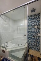 A modern bathroom with a glass-enclosed shower, a freestanding bathtub, and a patterned wall.