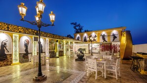 An outdoor dining area with white chairs and tables, ornate lamps, and a tiled floor. - Sterling Marbella Dehradun (Dehradun)
