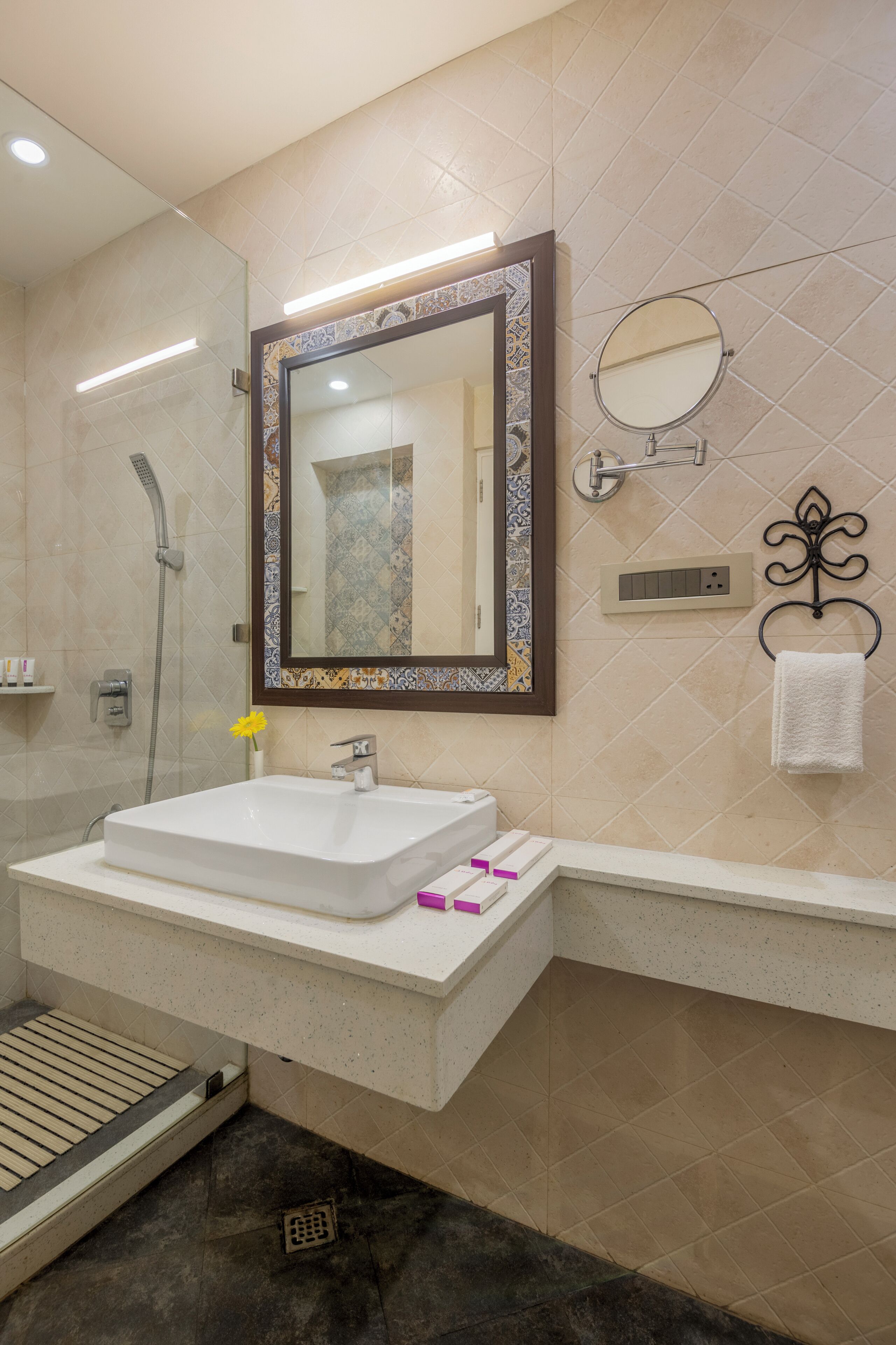 A bathroom with a large mirror, a sink, a shower, and a towel rack.