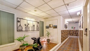 A hallway with patterned flooring, potted plants, and wall art. - Sterling Marbella Dehradun (Dehradun)