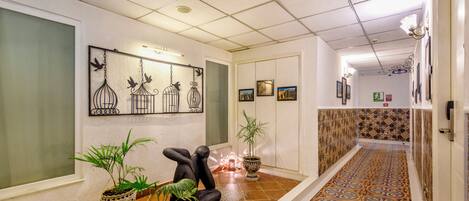Un pasillo con suelo estampado, plantas en macetas y cuadros en la pared.