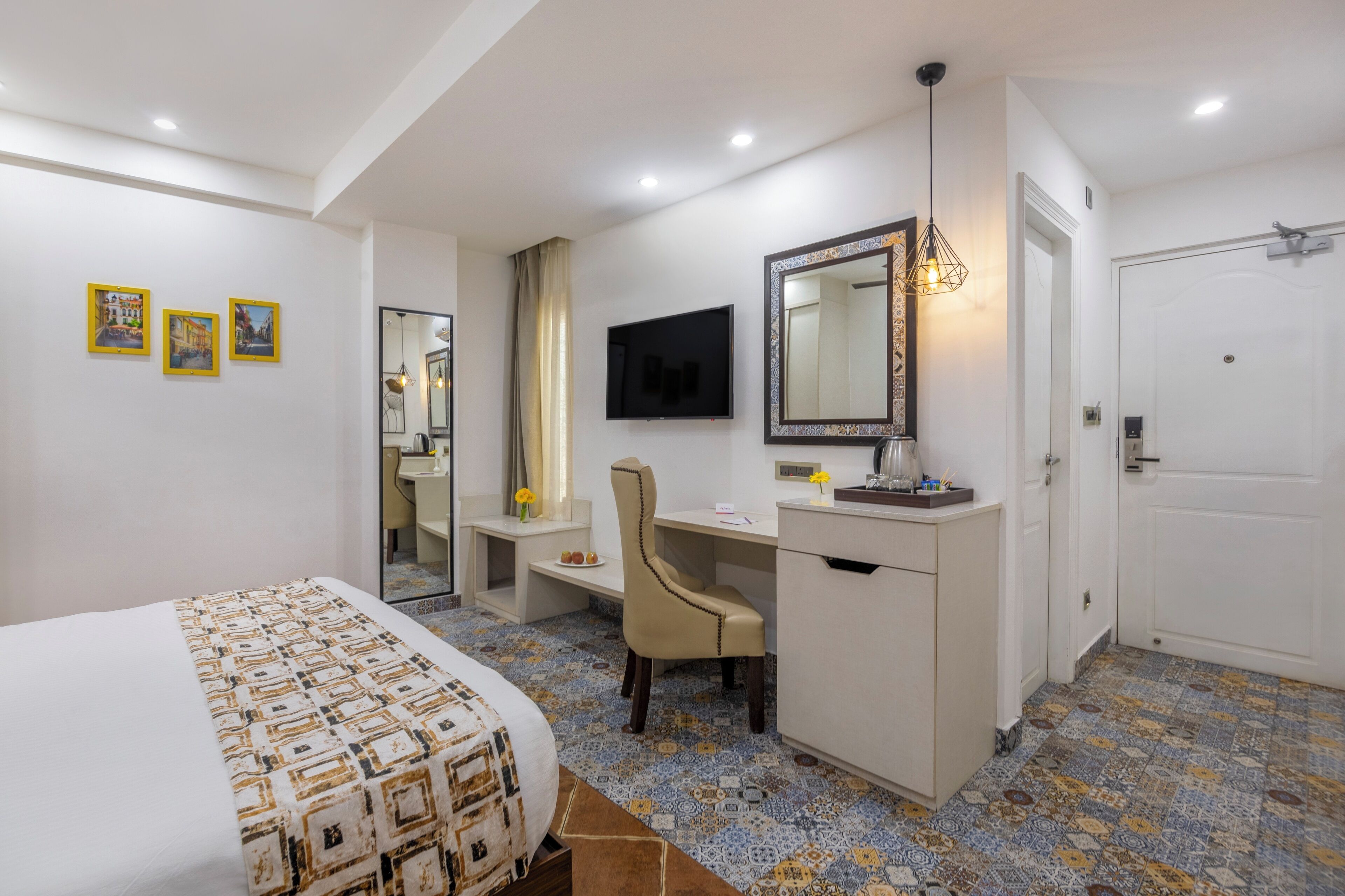 A hotel room with a bed, desk, chair, TV, and a door.