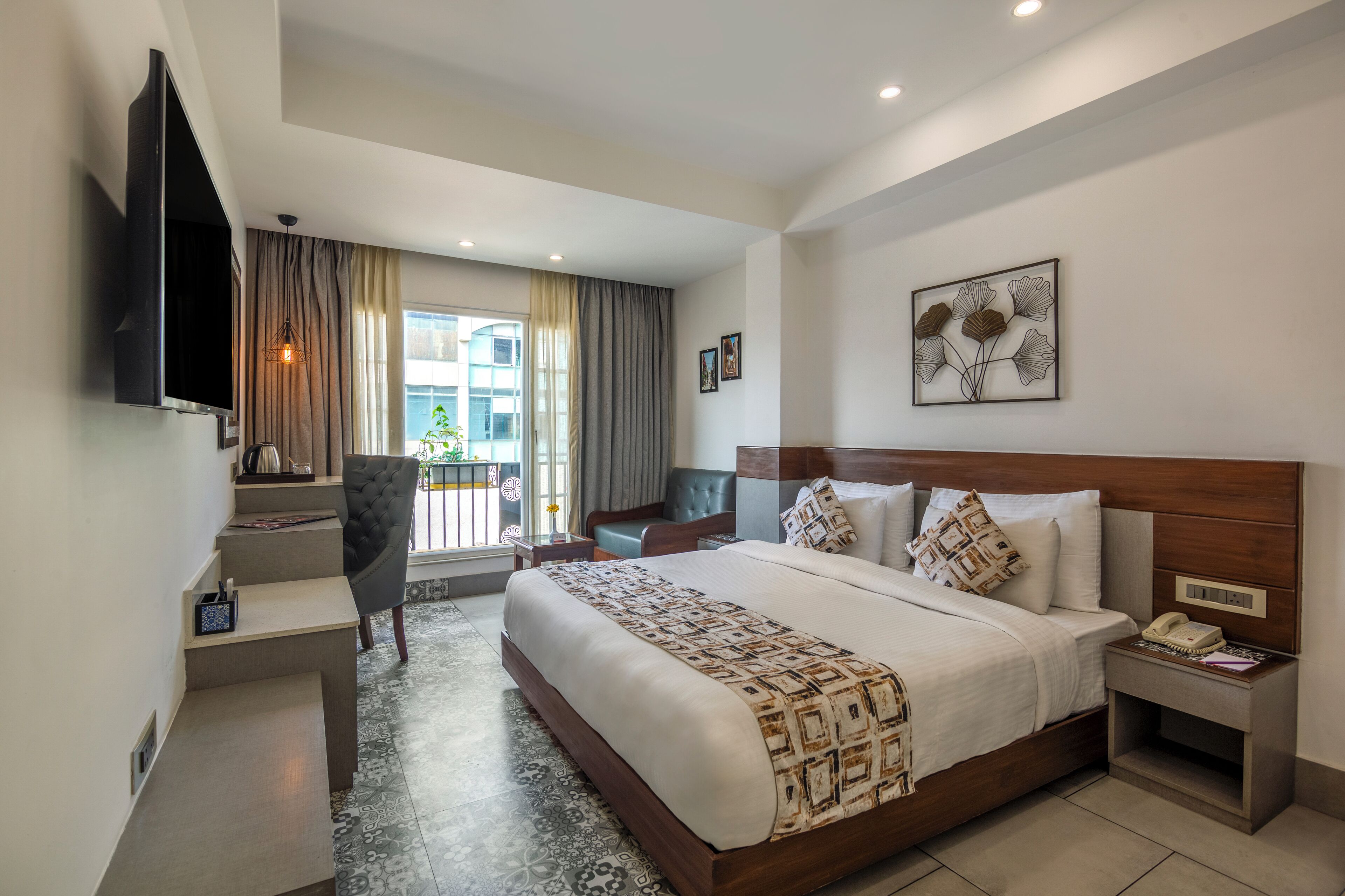 Une chambre d’hôtel moderne dotée d’un grand lit, d’un bureau avec une chaise, d’un téléviseur à écran plat et d’une fenêtre avec des rideaux.