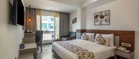 A modern hotel room with a large bed, a desk with a chair, a flat-screen TV, and a window with curtains.