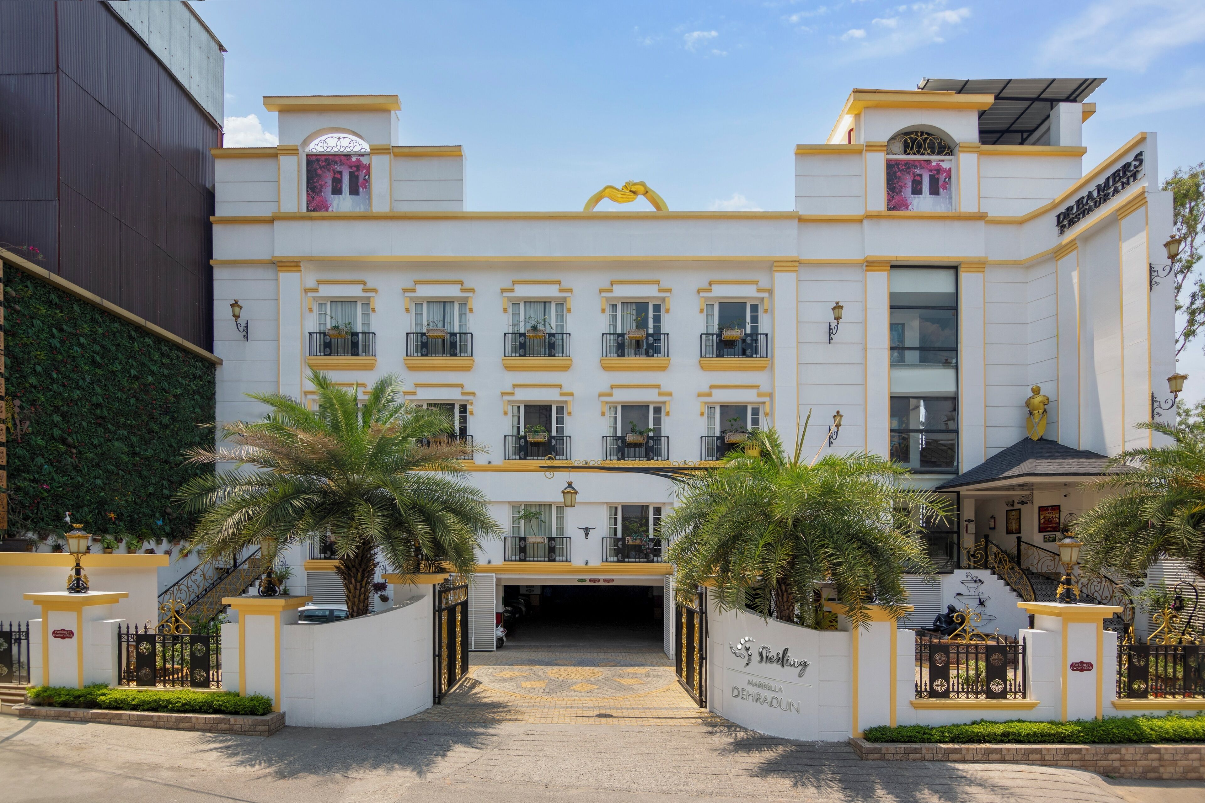 A hotel with a white facade, yellow trim, and a central entrance with a canopy.