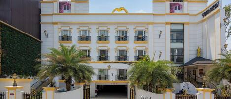 A hotel with a white facade, yellow trim, and a central entrance with a canopy.