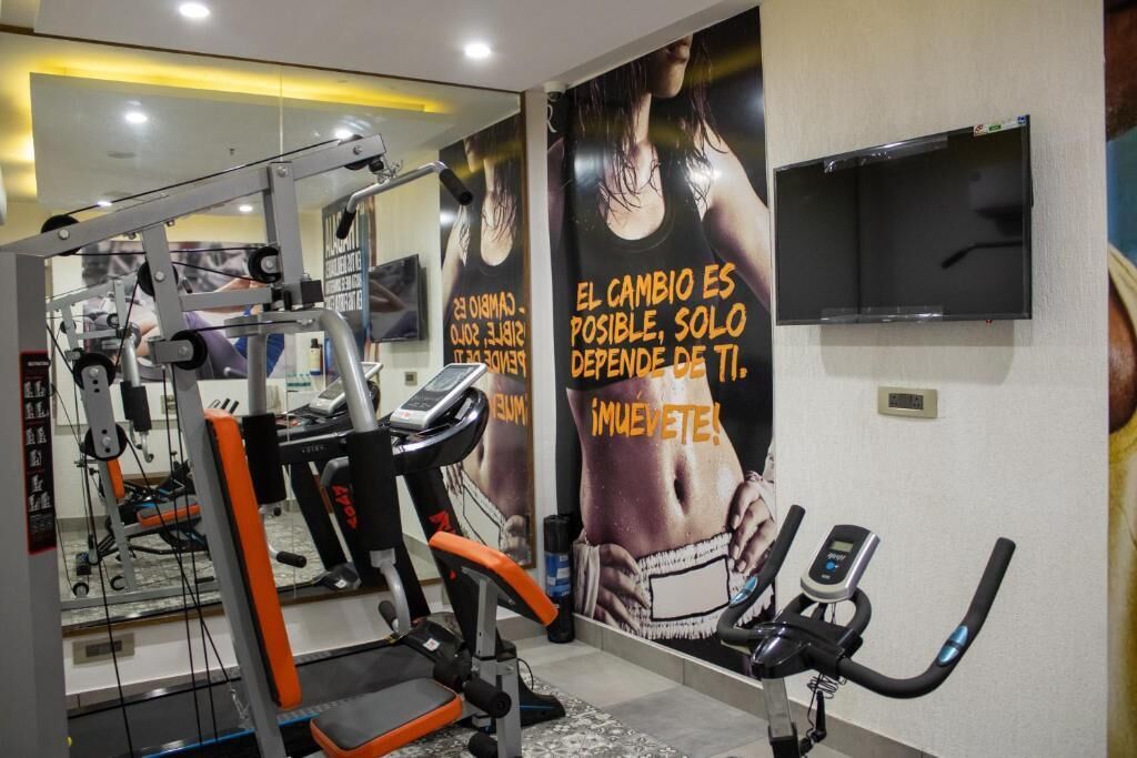 A gym with exercise equipment, a TV mounted on the wall, and motivational posters on the wall.