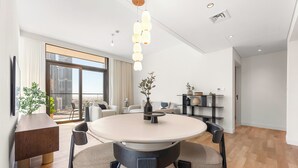 A modern dining area with a round table, chairs, and a hanging light fixture. - Stayis- Luxurious 2 BR near Burj Khalifa (Dubai)