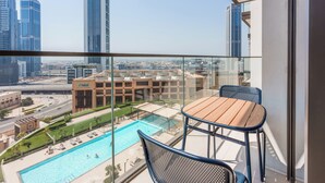 A balcony with a view of a swimming pool and cityscape. - Stayis- Luxurious 2 BR near Burj Khalifa (Dubai)