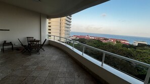 Enjoy the ocean views from this balcony with a tiled floor and seating area.