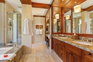 A modern bathroom with a large mirror, granite countertops, and wooden cabinetry.