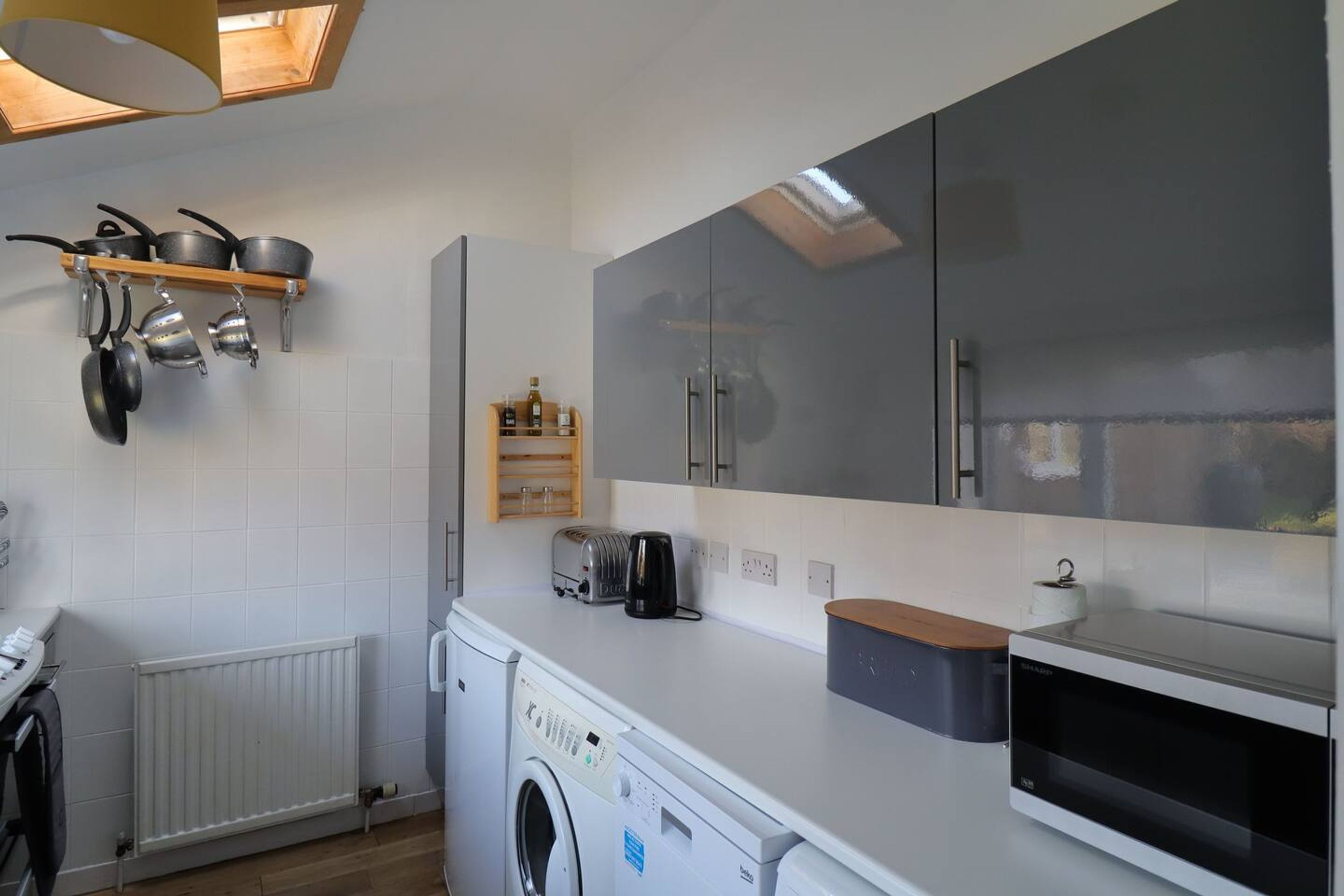 A compact kitchen with a washing machine, a microwave, and a toaster.