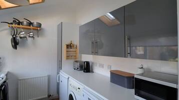 A compact kitchen with a washing machine, a microwave, and a toaster.