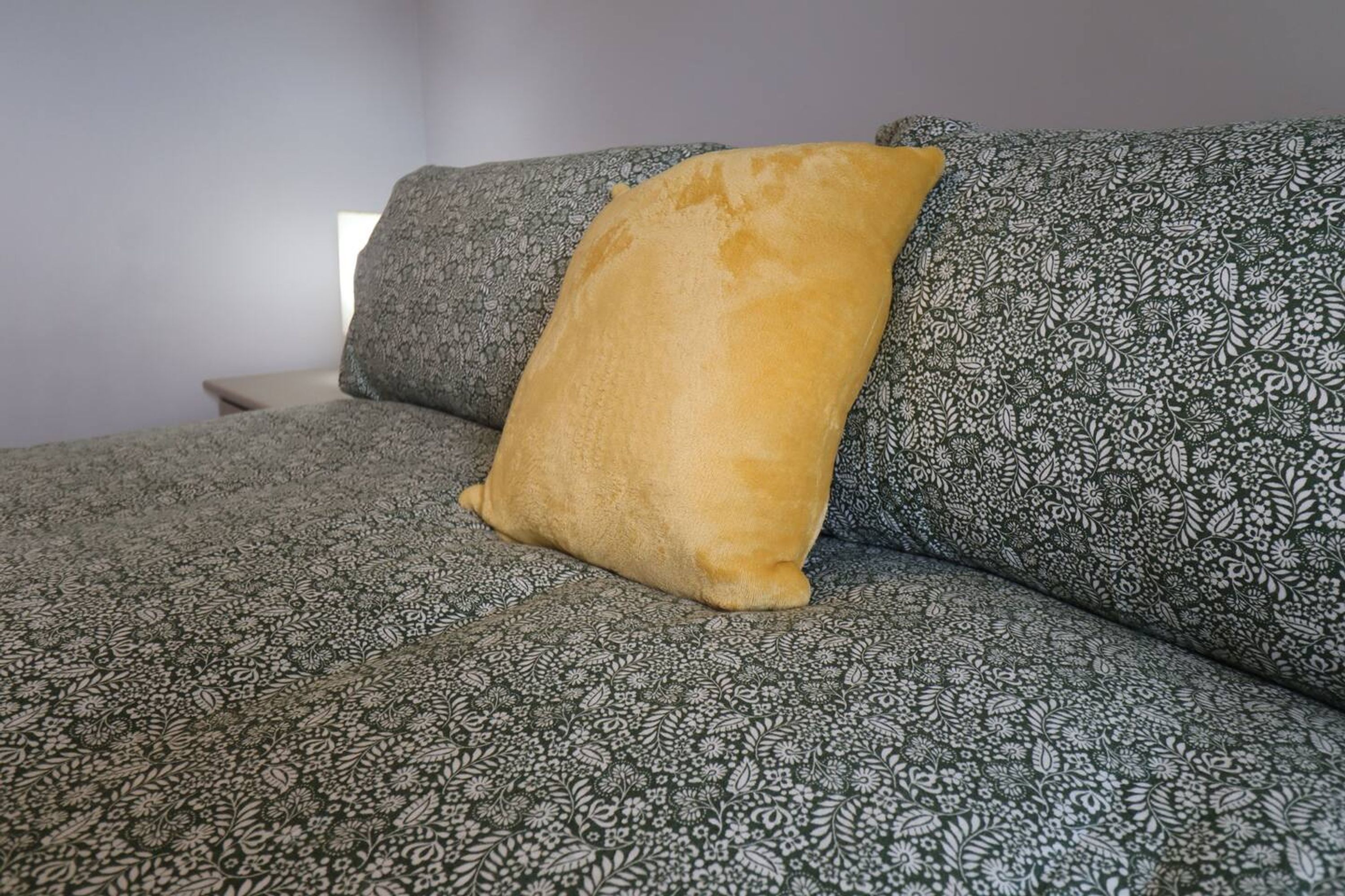 Un sofá con tela estampada y una almohada amarilla.