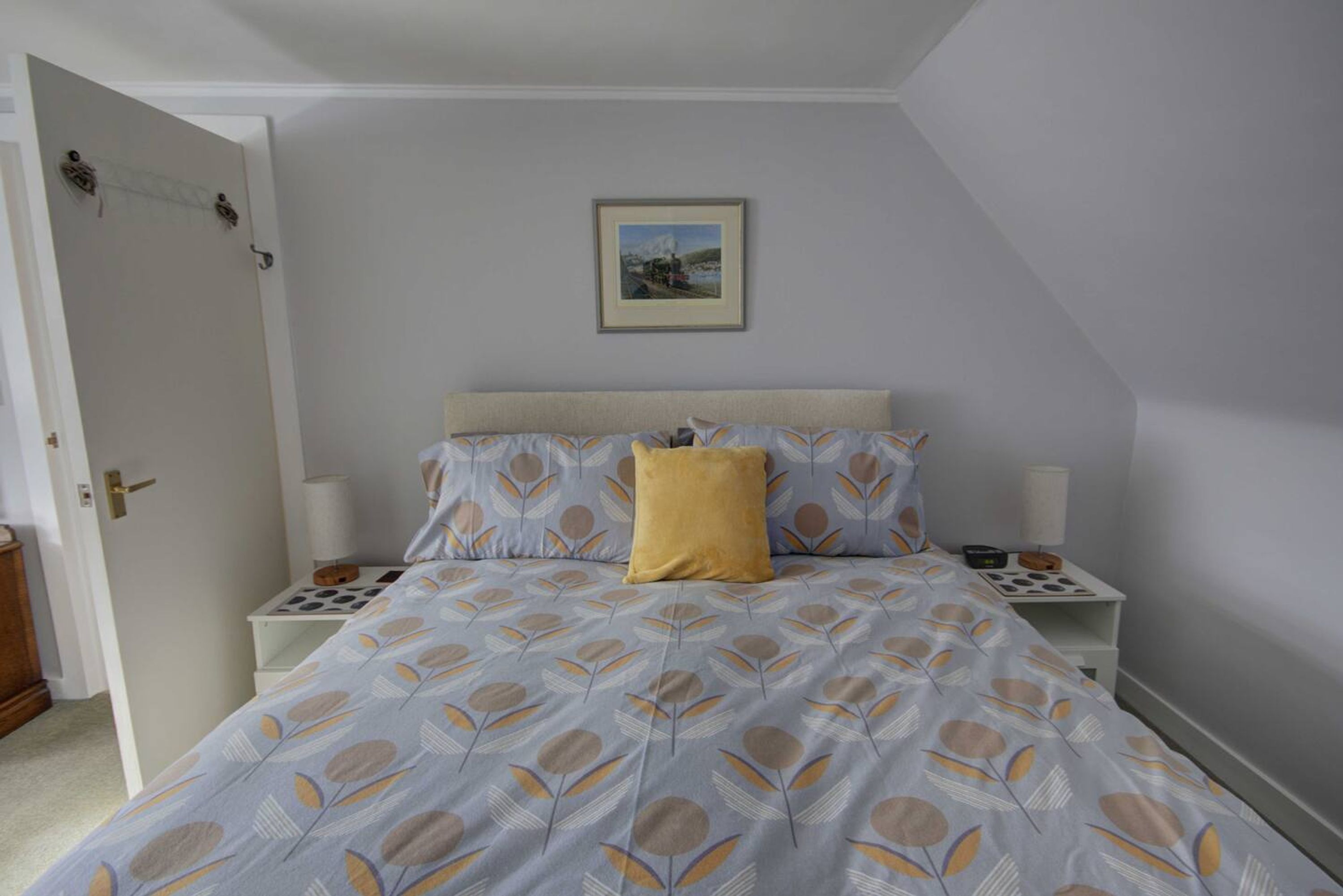 A bedroom with a bed, a nightstand, a bedside table, and a door.