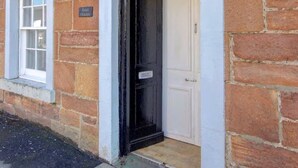 A brick building with a white-framed door and a small window to the left. - Anvil House Golspie (Golspie)