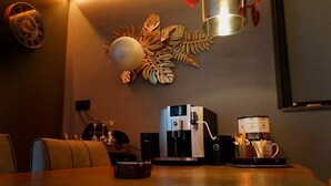 Zona de menjador amb una màquina de cafè, un rellotge i una decoració mural.