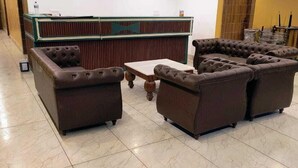 A lobby with a reception desk, a sectional sofa set, and a small coffee table. - Hotel Pinnacle Peaks (Joshimath)