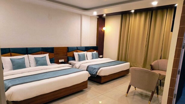 A hotel room with two beds, a chair, and a view of the street. - Hotel Pinnacle Peaks (Joshimath)
