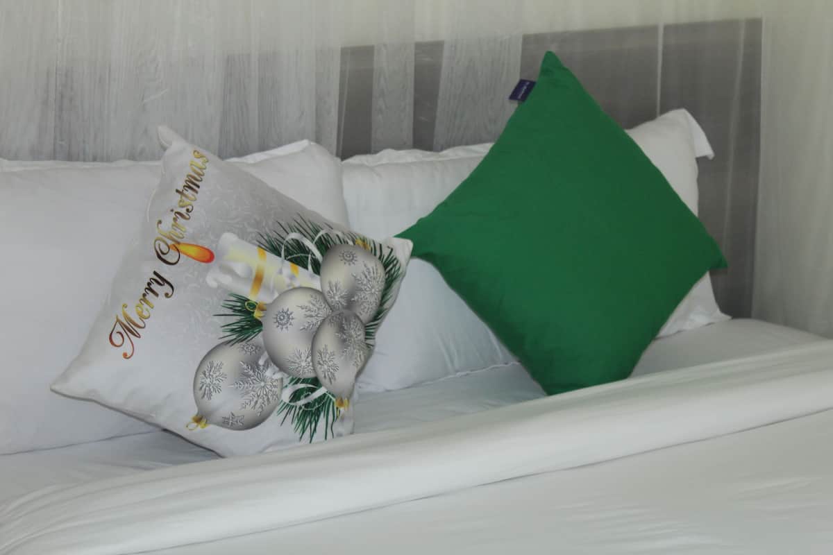 A bed with white bedding and a green pillow.