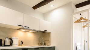 A modern kitchen with a built-in oven, a coffee maker, and a hanging clothes rack. - La Stanza del Principe (Naples)