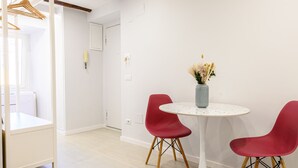 A modern dining area with a round table, two red chairs, and a vase with dried flowers. - La Stanza del Principe (Naples)