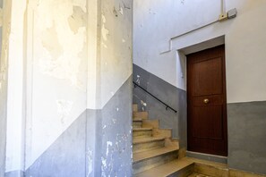 Una escalera con una puerta de madera al final, que conduce a una habitación con pintura descascarada en las paredes.
