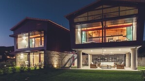 Una casa moderna de dos pisos con ventanas amplias, base de piedra y césped cuidado.