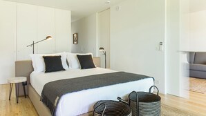 Un dormitorio moderno con cama, mesitas de noche y un sofá.