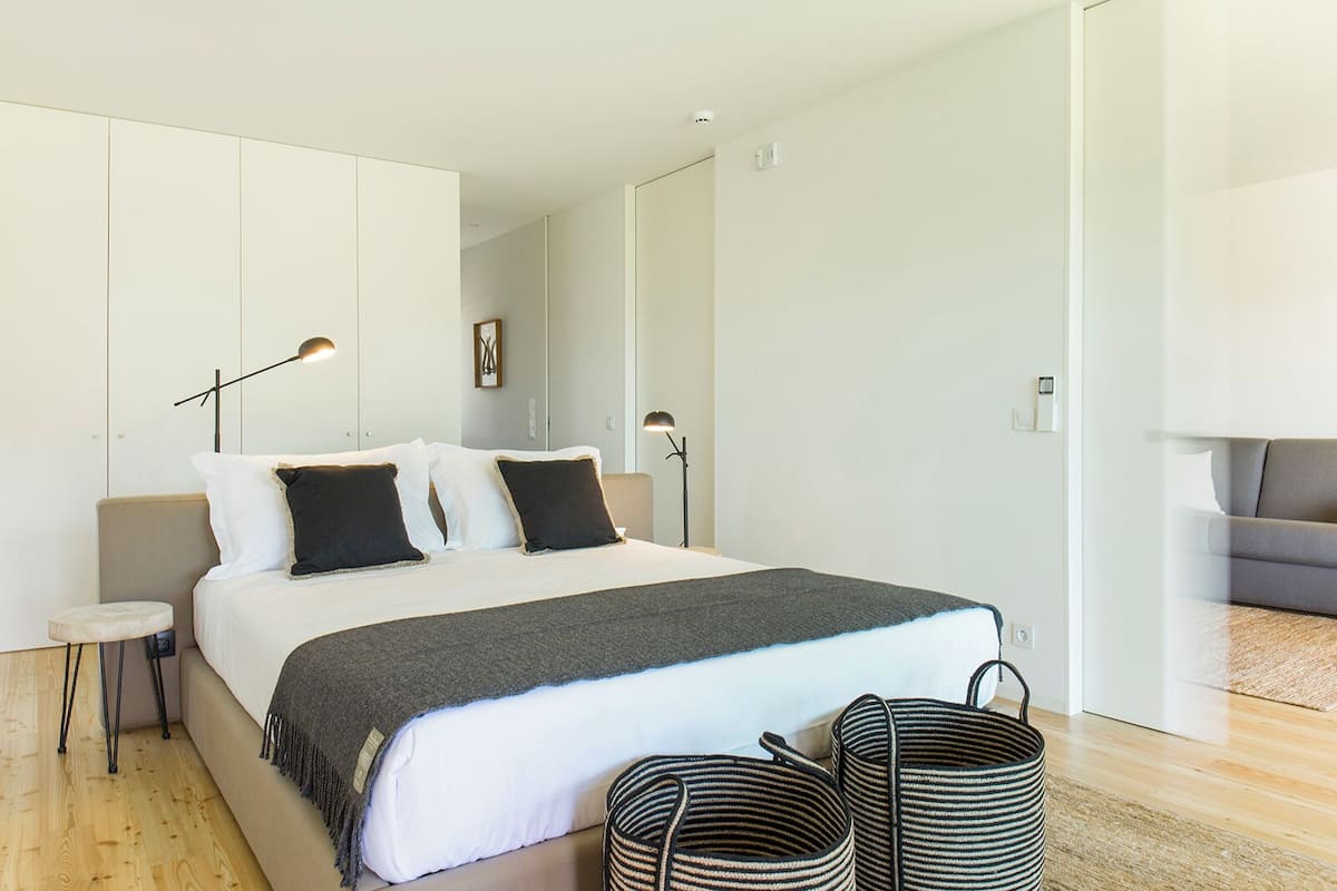 A modern bedroom with a bed, bedside tables, and a sofa.