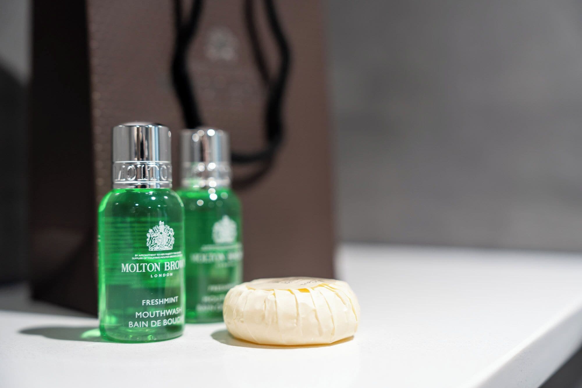 Two bottles of Molton Brown Freshmint mouthwash and a bar of soap on a white surface.