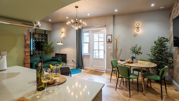 Eine moderne Küche mit Essbereich, ausgestattet mit einer gewölbten Decke, einem Kronleuchter und einem runden Holztisch mit Stühlen.