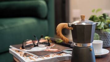 Eine Kaffeemaschine auf einem Tisch, zusammen mit einer Zeitschrift, Gläsern und einer Tasse.